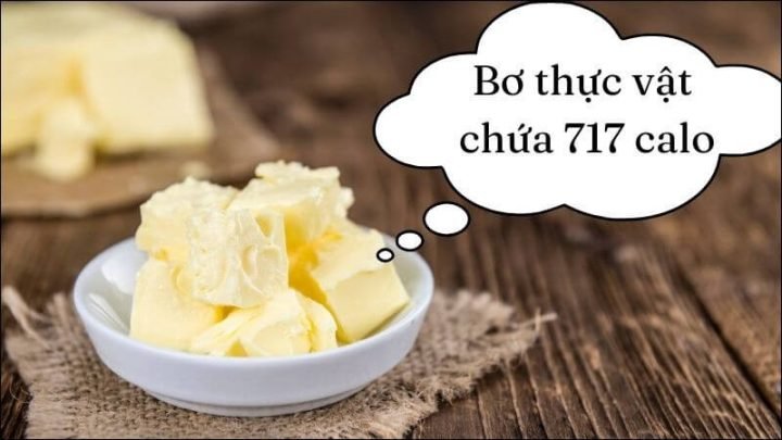 Một khối bơ thực vật trên đĩa gỗ, minh họa hàm lượng calo cao trong bơ thực vật