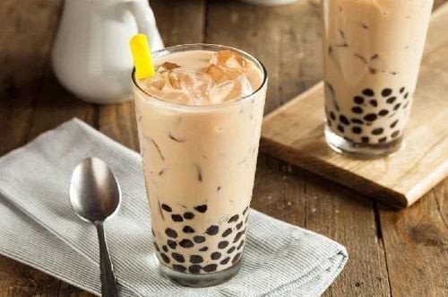 Một ly trà sữa trân châu với ống hút, đặt trên bàn gỗ, thể hiện lượng đường có thể ảnh hưởng sức khỏe.