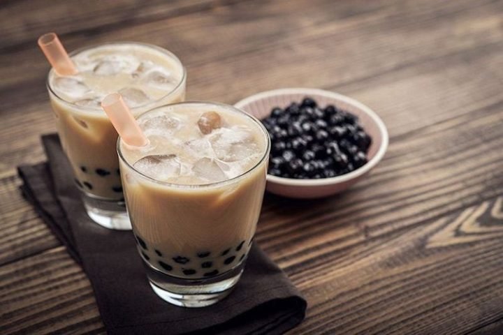 Một ly trà sữa xanh tươi mát không cồn, với lớp kem sữa béo ngậy và trân châu đen dưới đáy.