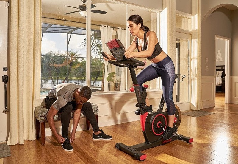 Một người đàn ông đạp xe trong nhà trên máy tập với tâm trạng vui vẻ