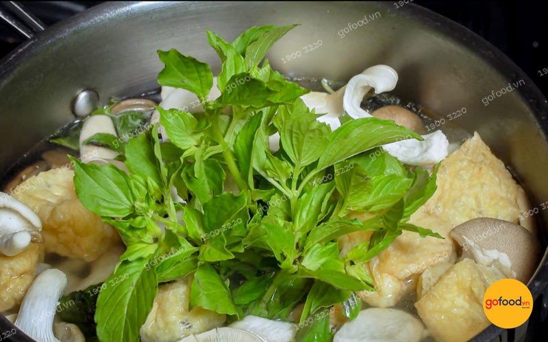 Một nồi lẩu nấm lá é chay với màu xanh tươi của lá é và các loại nấm hấp dẫn