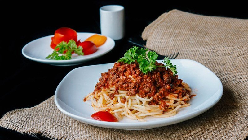 Người đàn ông đang ôm bụng khó chịu, gợi nhắc về vấn đề tiêu hóa khi ăn mì Ý.