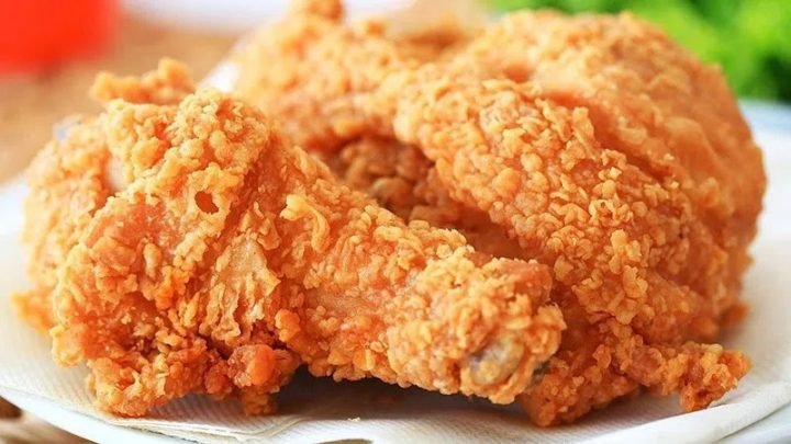 Người đang ăn nhiều gà rán, tượng trưng cho việc tiêu thụ quá mức có thể ảnh hưởng xấu đến sức khỏe. Phân tích 1 miếng gà rán KFC bao nhiêu calo.
