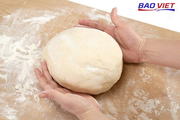 Người đang nhào khối bột mì đa dụng để làm bánh bao chay trên mặt bàn sạch