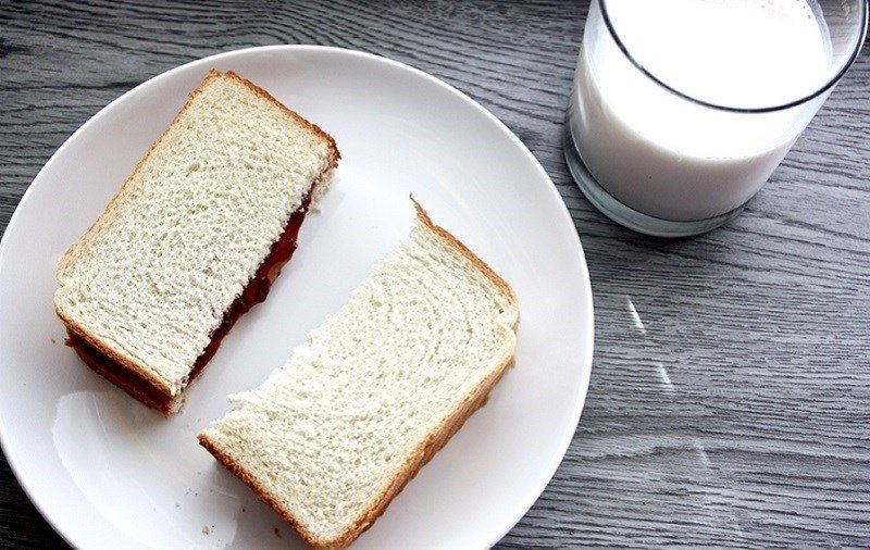 Người phụ nữ cân đo lượng bánh mì và thực phẩm để kiểm soát một lát bánh mì bao nhiêu calo và giữ dáng.