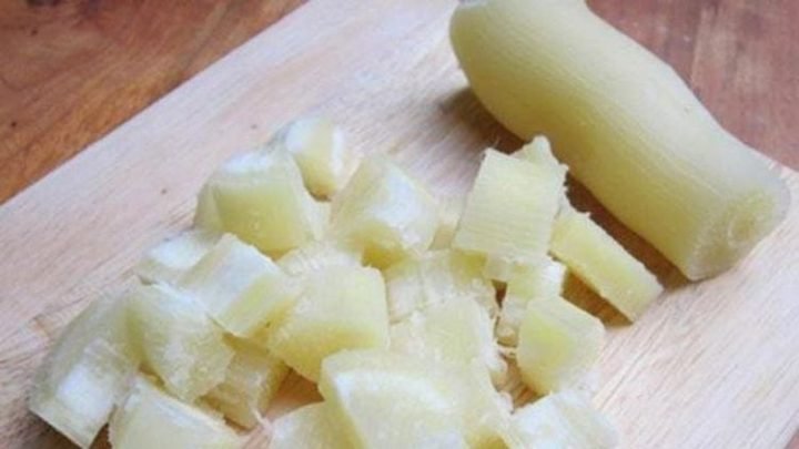 Người phụ nữ đang cầm củ sắn luộc, suy nghĩ về lượng calo và giảm cân.