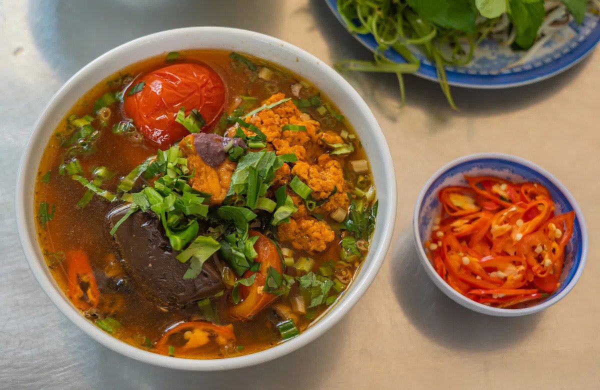 Người phụ nữ đang thưởng thức bún riêu cua với lượng bún vừa phải, một bí quyết để kiểm soát calo riêu cua và tổng thể món ăn