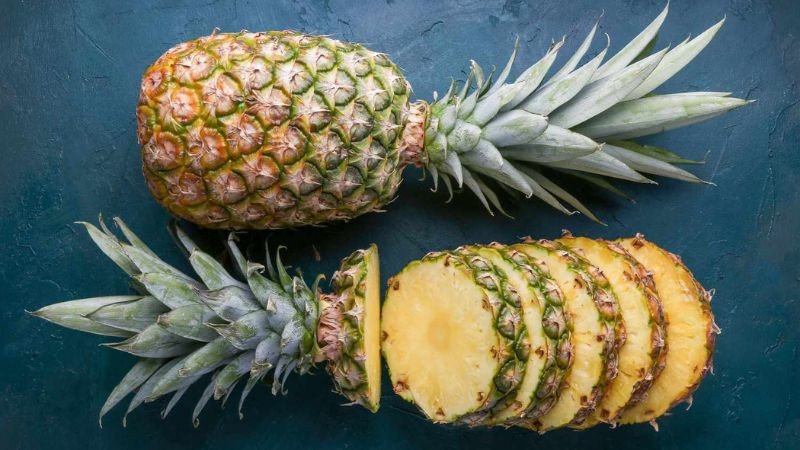 Người phụ nữ hạnh phúc đang ăn miếng thơm (dứa), thể hiện việc thưởng thức trái cây lành mạnh giúp kiểm soát cân nặng.