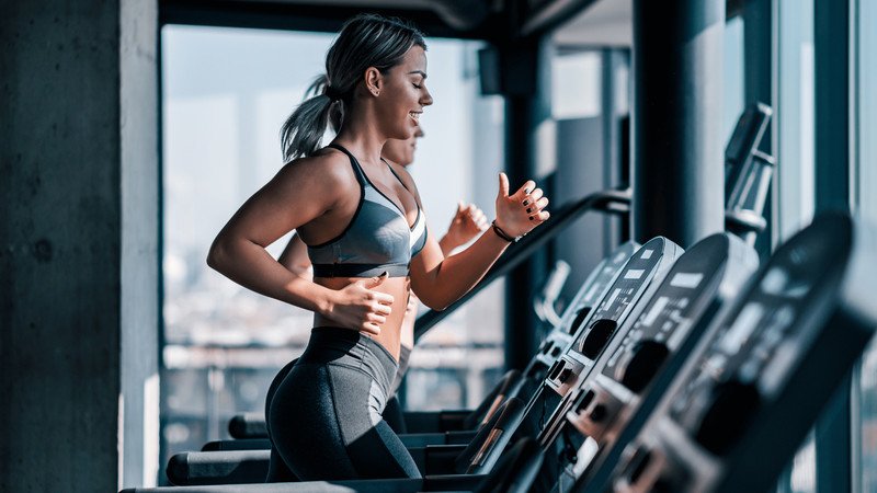 Người phụ nữ khởi động nhẹ nhàng, chuẩn bị cho buổi tập gym tiêu hao calo.