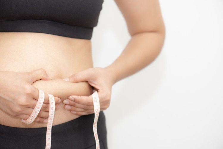 Người phụ nữ kiểm tra vóc dáng, minh họa hiệu quả giảm cân và đốt mỡ thừa từ hoạt động đạp xe.