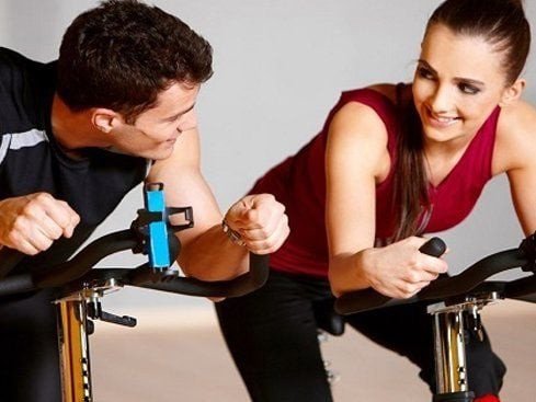 Người phụ nữ tập đạp xe trong nhà, một hình thức tập aerobic hiệu quả để đốt cháy calo.