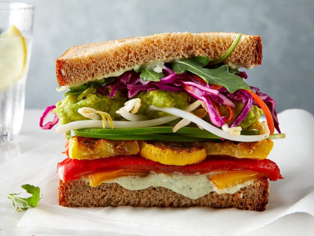Người phụ nữ thưởng thức bánh mì sandwich với trái cây và nước cam tươi