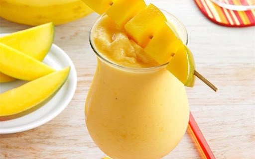 Người phụ nữ thưởng thức ly sinh tố xoài mát lạnh, một lựa chọn lành mạnh.
