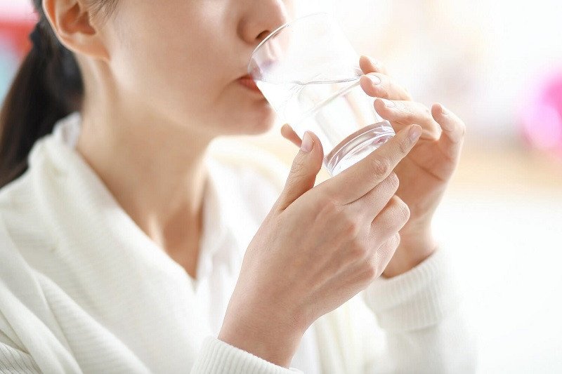 Người phụ nữ uống một ly nước lọc để tăng cường hydrat hóa