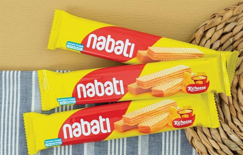 Nhiều gói bánh Nabati phô mai xếp chồng lên nhau, minh họa các kích cỡ và bao bì khác nhau, nhấn mạnh sự đa dạng của sản phẩm