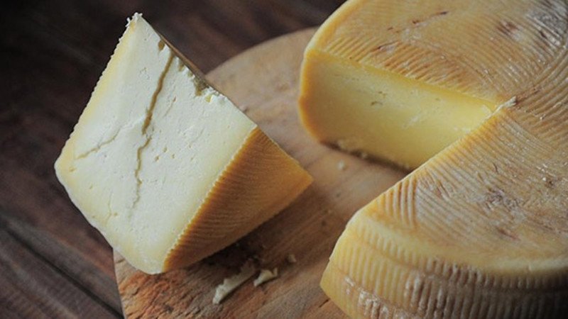 Những miếng phô mai tươi ngon đa dạng đặt trên nền gỗ, thể hiện lợi ích dinh dưỡng