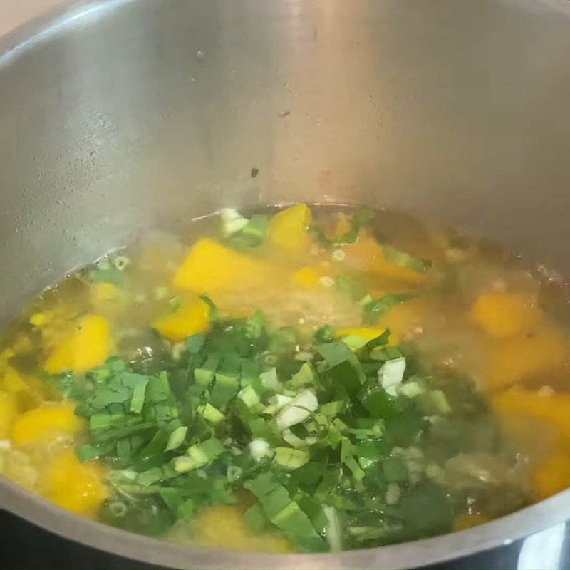 Nồi canh bí đỏ đang được nấu sôi với các loại rau gia vị