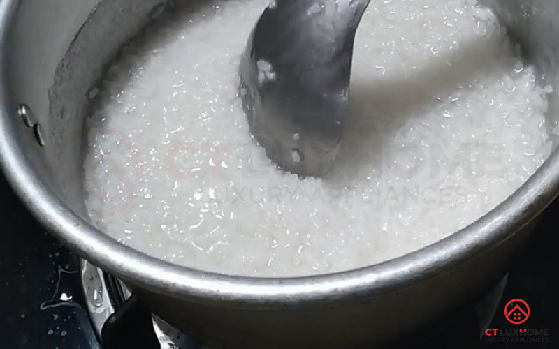 Nồi cháo bị cháy dưới đáy, người phụ nữ đang cố gắng cạo sạch phần cháy.