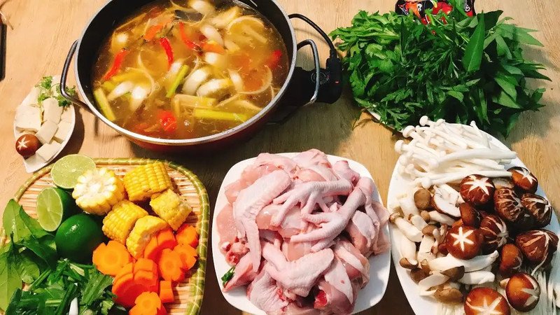 Nồi lẩu gà thập cẩm bốc khói cùng bún và rau ăn kèm