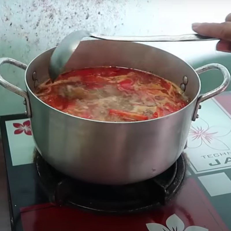 Nồi nước dùng bún xương heo cà chua đang sôi nhẹ, dậy mùi thơm