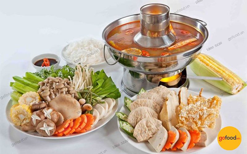 Nồi nước lẩu Thái chay đang sôi trên bếp, với màu đỏ cam hấp dẫn từ cà chua và sả ớt, biểu tượng cho cách nấu lẩu Thái chay tại nhà.