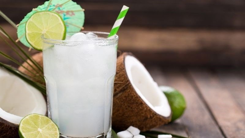 Nước dừa trong cốc và dừa tươi trên nền gỗ