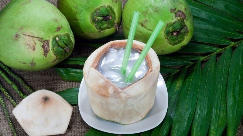 Nước dừa trong ly với những miếng dừa tươi và lá xanh