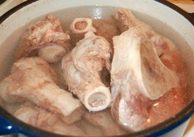 Nước dùng bún cá chấm đang được ninh với xương, cá và cà chua