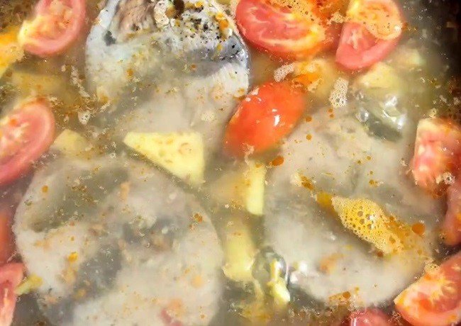 Nước dùng bún cá ngừ đang sôi, với cà chua và dứa tạo màu đẹp mắt