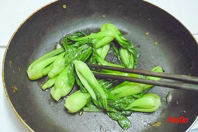 Quá trình xào rau cải trên chảo lớn với tỏi phi thơm