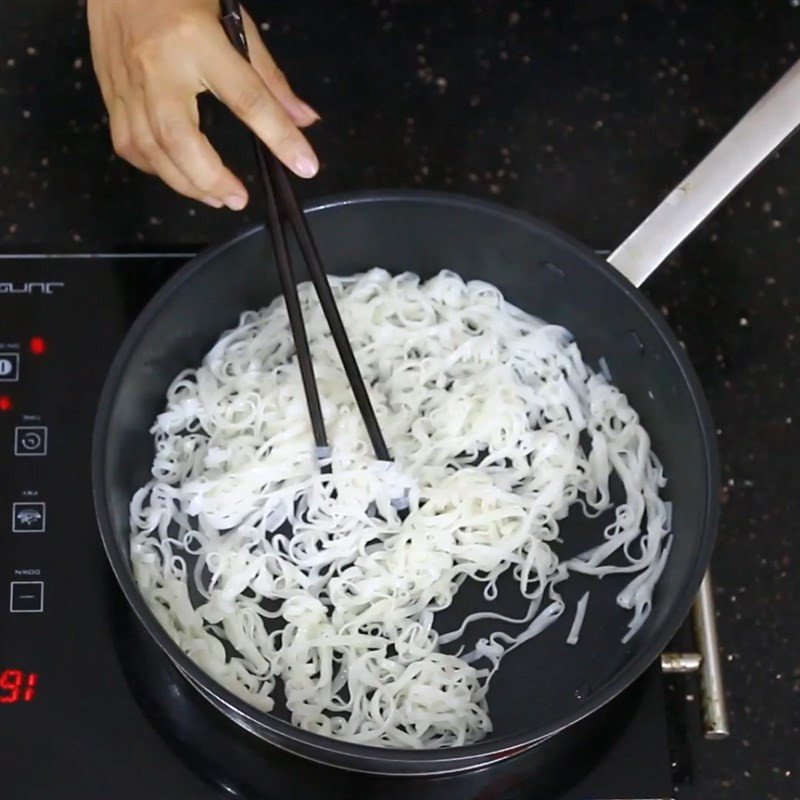 Rau cải xanh tươi được xào nhanh trong chảo để giữ độ giòn, làm tăng hương vị cho món mì gạo xào
