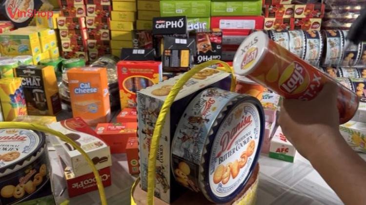 Sắp xếp các loại bánh kẹo và đồ uống vào giỏ quà theo bố cục hợp lý
