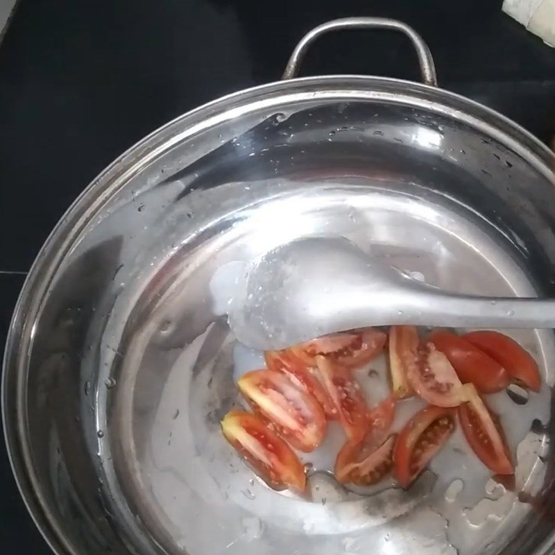Thả từng khúc cá trắm vào nồi lẩu đang sôi, bắt đầu quá trình nấu chín.
