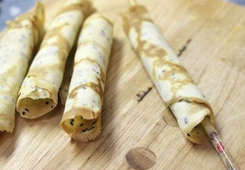 Thao tác cuộn bánh kẹp cuốn nhanh tay khi bánh còn nóng để tạo hình đẹp mắt