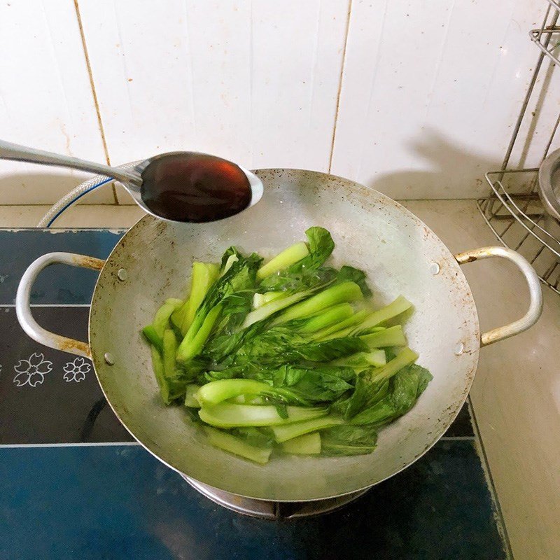 Thêm dầu hào và các loại gia vị vào cải thìa đang xào