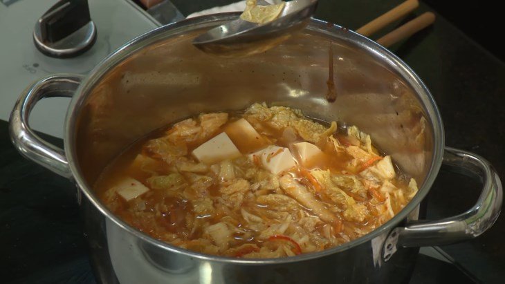 Thêm đậu phụ vào nồi canh kim chi đang nấu