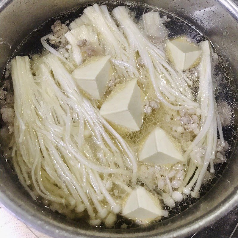 Thêm nấm kim châm và đậu hũ vào nồi canh rong biển đang sôi