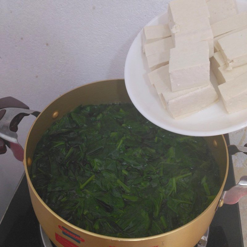 Thêm rau mồng tơi vào nồi canh chay đang sôi