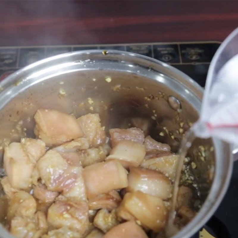 Thịt ba chỉ đang được kho trong nồi cùng nước dừa và trứng vịt