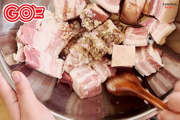 Thịt ba chỉ thái miếng vuông đang được ướp cùng các loại gia vị để chuẩn bị làm món thịt kho trứng