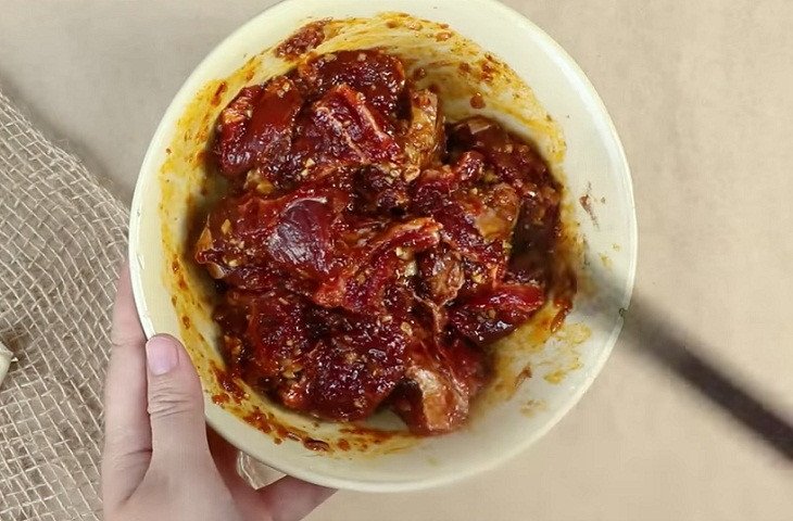 Thịt bò nạm gân đã cắt miếng và đang được ướp với gói gia vị bò kho đậm đà