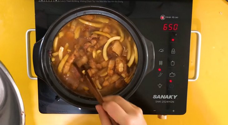 Thịt heo và dừa tươi đang được xào săn trong nồi trước khi thêm nước dừa để kho