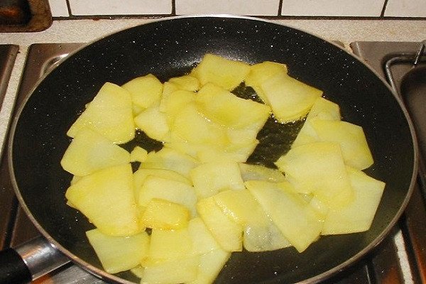 Thực hiện cách xào khoai tây với cà chua trên chảo nóng