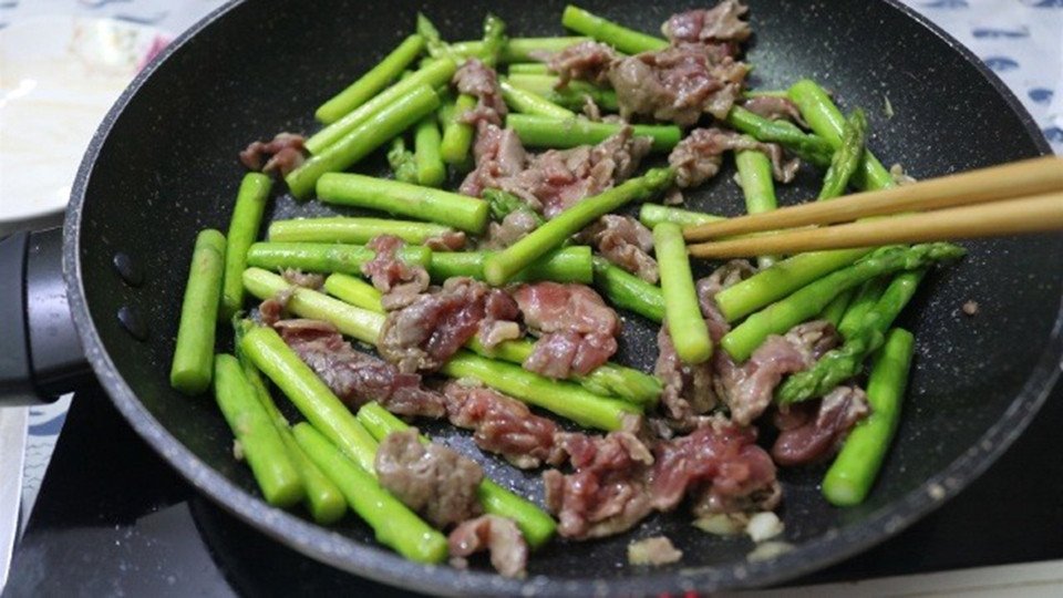 Thực hiện món xào măng tây với thịt bò trên bếp