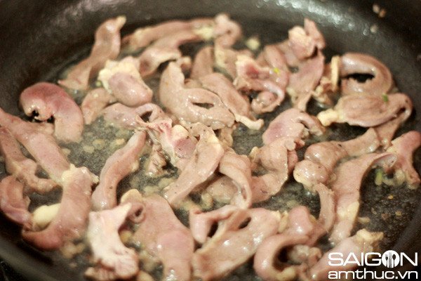 Tim heo đang được xào chín tới trong chảo với hành tím phi thơm
