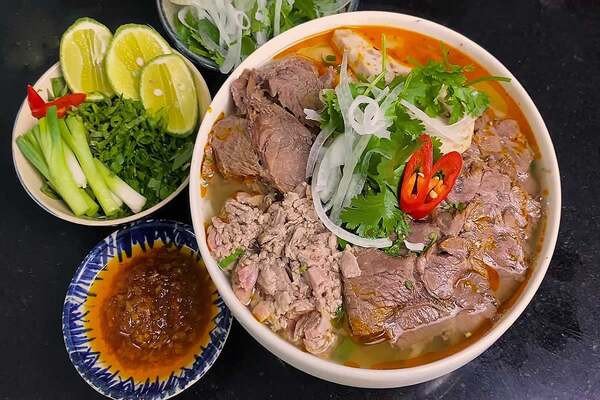 Tô bún bò tái nóng hổi đầy đủ thịt và rau thơm