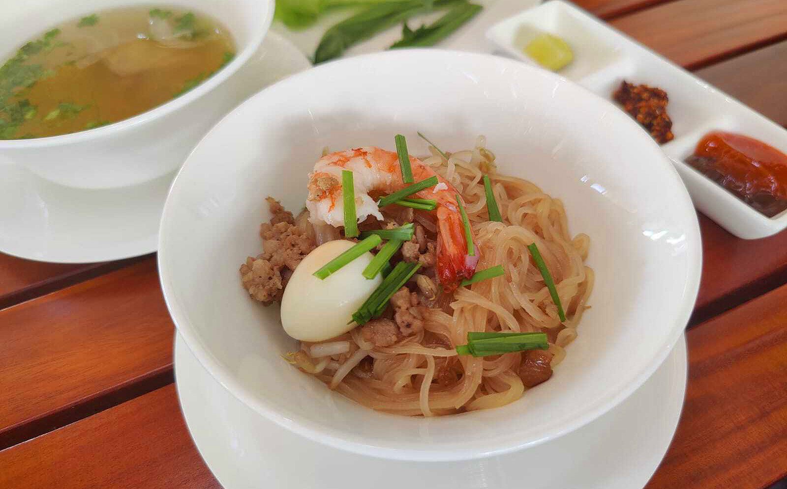 Tô hủ tiếu khô với sợi dai, thịt xá xíu, trứng cút và nước sốt đặc trưng