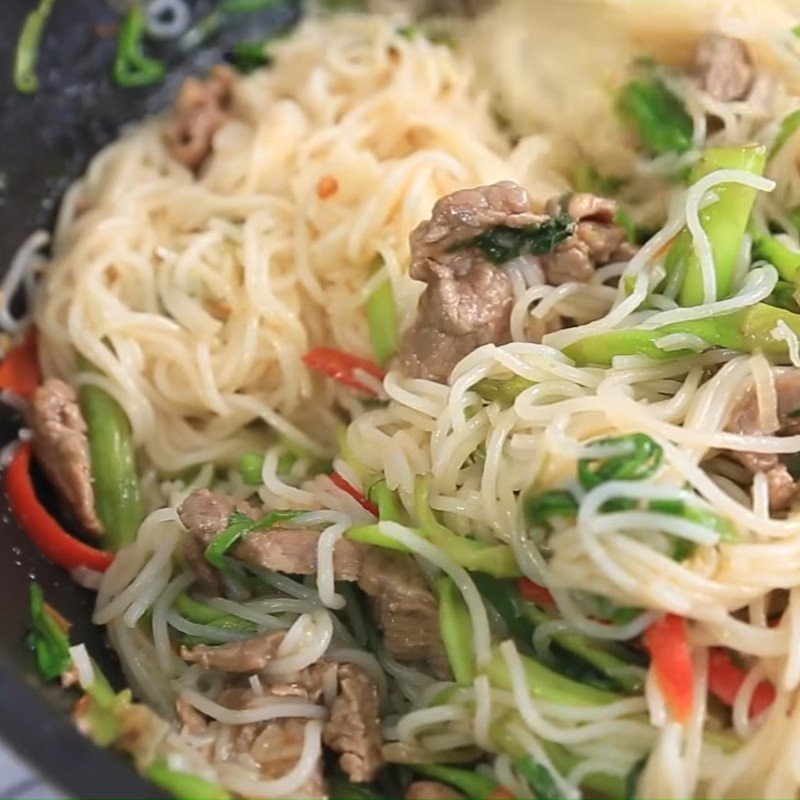 Trộn đều bún với thịt bò và rau cần trên chảo