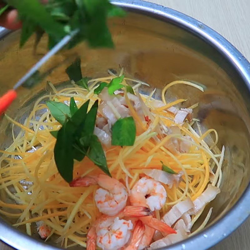 Trộn đều các nguyên liệu gỏi đu đủ tôm thịt trong thau lớn
