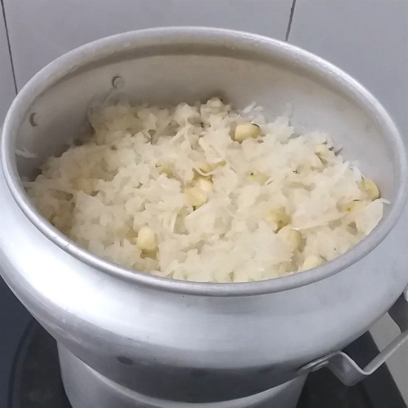 Trộn đều dừa nạo và hỗn hợp nước cốt dừa vào xôi hạt sen sau khi hấp, giúp xôi ngấm đều vị.